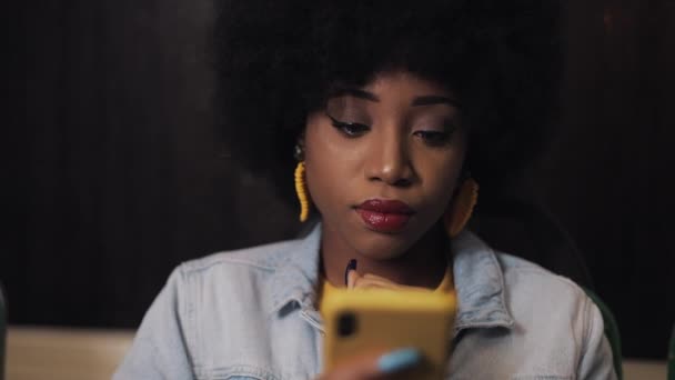 Smutna młoda African American kobieta za pomocą smartfona w transporcie publicznym. Czas nocny. — Wideo stockowe