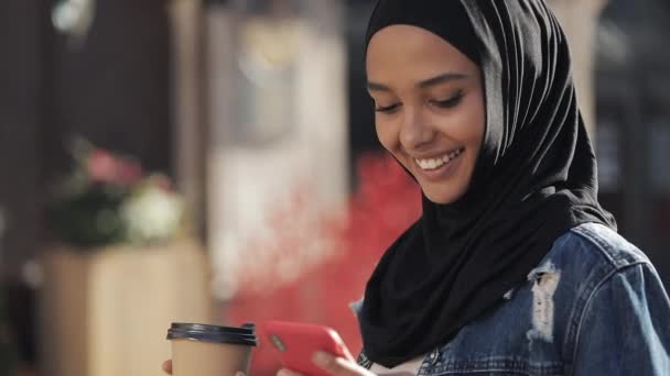 Wanita muslim muda mengirim pesan suara audio di ponsel di luar ruangan berbicara dengan asisten mobile. Gadis yang menggunakan smartphone voice recognition, mendikte pikiran, pesan panggilan suara — Stok Video