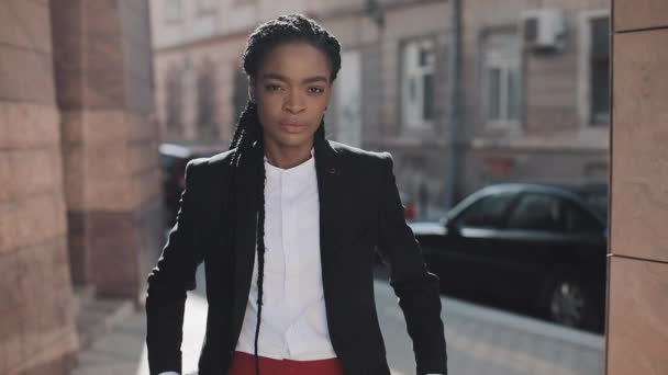 Porträtt av allvarliga afroamerikansk affärskvinna stående på den gamla gatan och passerar händerna. Hon tittar på kameran och ler. Svart snygg. Dreadlocks. Afro frisyr. — Stockvideo