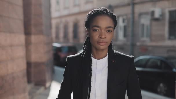 Portrait of serious African American business woman standing on the old street near business centre. She looking at the camera and smiling. Black Stylish. Dreadlocks. Afro Hairstyle. — Stock Video