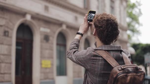 戴眼镜的嬉皮士家伙在他的相机手机上拍照,在欧洲旅行。游客男子拍照与相机手机外. — 图库视频影像