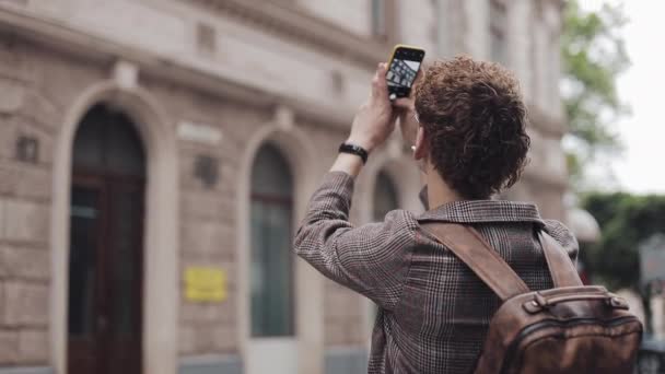 Hipster man met bril het nemen van foto op zijn camera telefoon reizen in Europa. Toerist man het nemen van foto met camera telefoon buiten. — Stockvideo