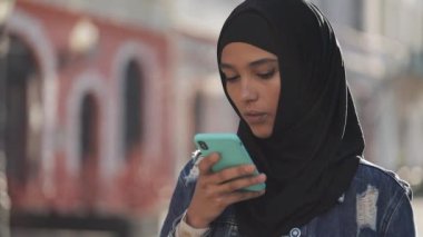 Genç Müslüman kadın cep telefonda sesli mesaj gönderme açık mobil asistan konuşurken. Kız akıllı telefon ses tanıma kullanarak, düşünceler, Sesli çevirme mesajı dikte