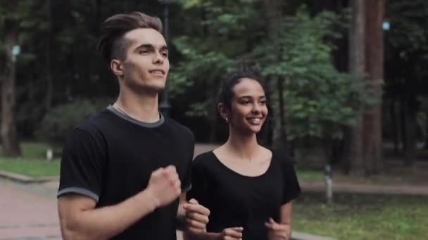 Couple qui a l'air excité Porter une combinaison de jogging Sourire et bavarder Courir dans le parc Concept Mode de vie sain Vue de côté . — Video