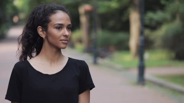 Portrait d'une jeune femme heureuse tournant la tête, souriante et debout dans le parc Gros plan . — Video
