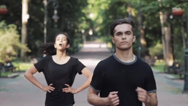 Young Man and Girl Running in the Park Girl Gets Tired and Stopped Man Continue Running Concept Healthy Lifestyle . — Stock Video