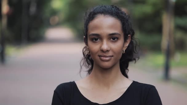 Portrait d'une jeune femme heureuse souriante et debout dans le parc Gros plan . — Video