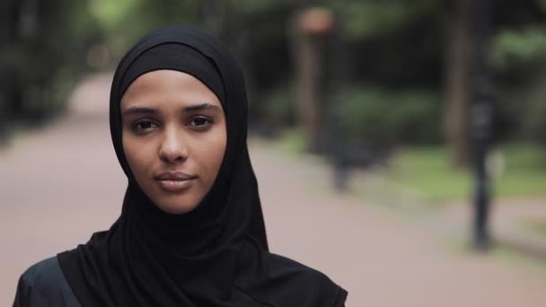 Porträt eines glücklichen jungen muskulösen Mädchens mit Hijab, das lächelt und in Nahaufnahme im Park steht. — Stockvideo