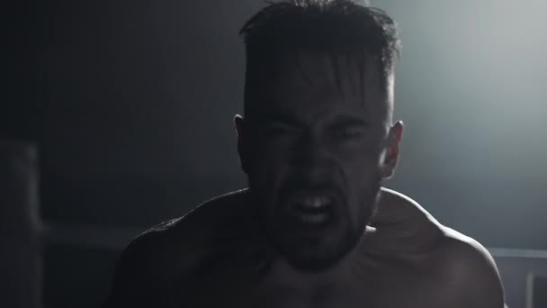 Wütender Mann mit Boxhandschuhen schreit emotional in die Kamera, die auf dem Boxring steht. Zeitlupe. — Stockvideo