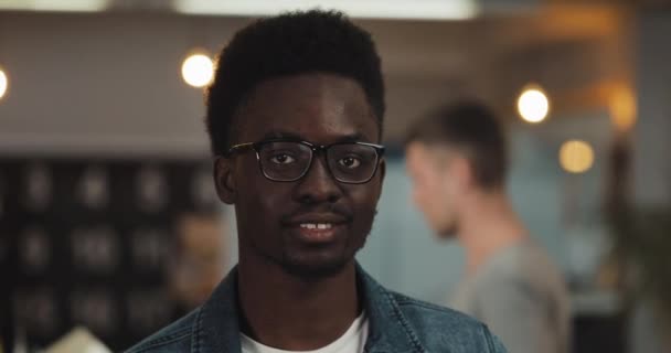 Porträt eines jungen, schwarz lächelnden erfolgreichen Geschäftsmannes mit stylischer Brille im modernen Büro. Nahaufnahme. Berufstätige auf verschwommenem Hintergrund. — Stockvideo