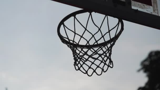 Back Side View of Ball Scoring into Basket in Slow Motion against Evening Sky Background (engelsk). Frisk livsstil og sportskonsept . – stockvideo