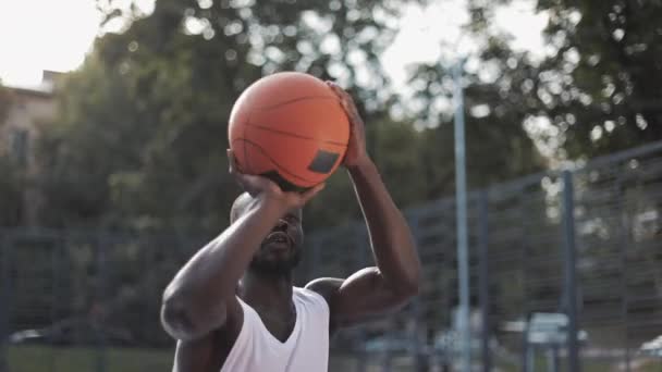 Widok z boku Młody Przystojny Muskularny Afro American Guy w białym Singlet z poważnym twarzy Rzucanie piłki do koszyka, Trening w Street Basketball Court. Zdrowy styl życia i koncepcja sportu. — Wideo stockowe