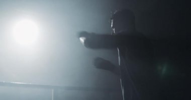 Erkek boksör, karanlık ringde eğitim almış. Yavaş çekim. Siluet. Boks konsepti.