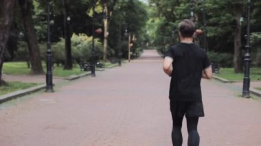 Kulaklıklı Kafkasyalı Genç Adam Park Arkasında Koşan Koşu Takımlı Sağlıklı Yaşam Tarzı Konsepti.