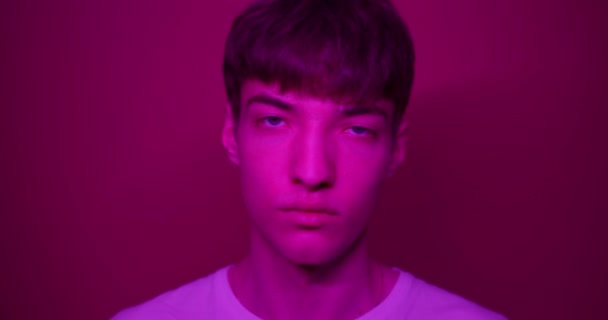 Retrato de Young Millenial Stylish Guy vestindo camiseta branca olhando direto para a câmera em pé no Futuristic Neon Pink Lights. Estilo de vida e conceito de pessoas . — Vídeo de Stock