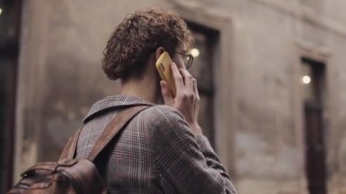 Old City Caddesi 'nde yürürken Çantalı Genç Adam' ın Telefonla Konuşması. İletişim, Öğrenci Konsepti.