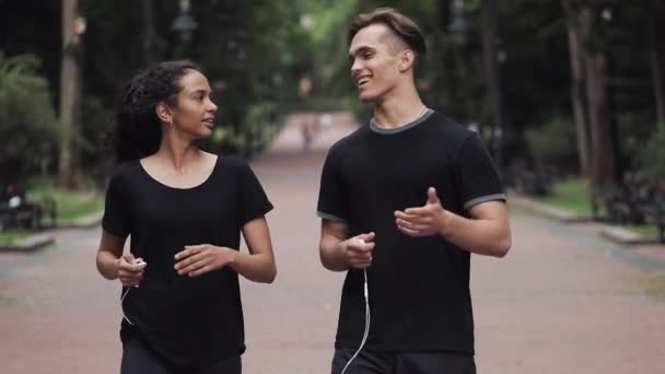 Young Man and Muslin Girl Talking Smiling and Holding Headphones in Their Hands Looking Happy Walking in the Park People Concept. — Stok Video