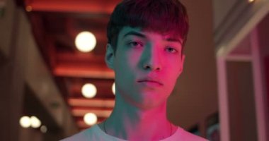 Fütürist Neon Kulüp Işıkları Arkaplanında Beyaz tişörtlü genç adam portresi. Yakın çekim çekim. Yaşam Tarzı ve İnsanlar Konsepti.