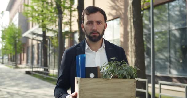 Portret van een jongeman in pak met z 'n spullen op straat. Mannelijke kantoormedewerker in de 30 verloor zijn baan en keek teleurgesteld. Begrip werkloosheid en crisis. — Stockvideo