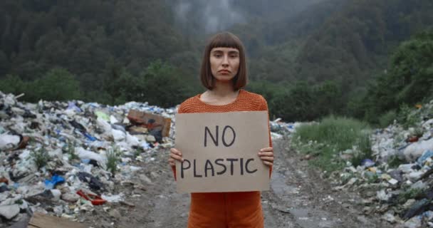 Una activista sin póster de plástico cerca de pastillas de basura en el bosque. Mujer milenaria apoyando el movimiento de huelga de ecología. Concepto de contaminación ambiental y salvar la Tierra . — Vídeos de Stock