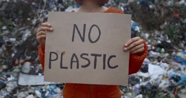 Vista de la cosecha de la mujer levantando cartel de cartón sin escritura de plástico. Persona femenina protestando contra la contaminación de la tierra mientras está de pie frente a la colina de la basura. Concepto de ecología . — Vídeos de Stock