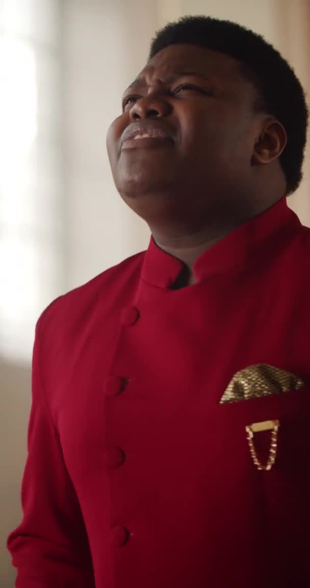 Kırmızı takım elbiseli Afro-Amerikan gospel şarkıcısına yakından bakın. Genç adam duygusal olarak ibadet müziği yapıyor ve vücudunu hareket ettiriyor.. — Stok video