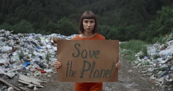 Beskär utsikt över flicka aktivist med Spara Planet ekologi affisch promenader nära papperskorgen piller. Ung kvinna som stöder klimatstrejkrörelsen. Begreppet föroreningar och rädda Moder Jord. — Stockvideo