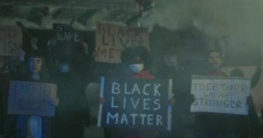Siyahi hayatı olan afiş tutan Afro-Amerikalı kız eylemci sokakta duman içinde dururken yazmakla ilgili. Polis şiddetine karşı ayaklanırken insanlar bağırıyor ve slogan atıyorlar..
