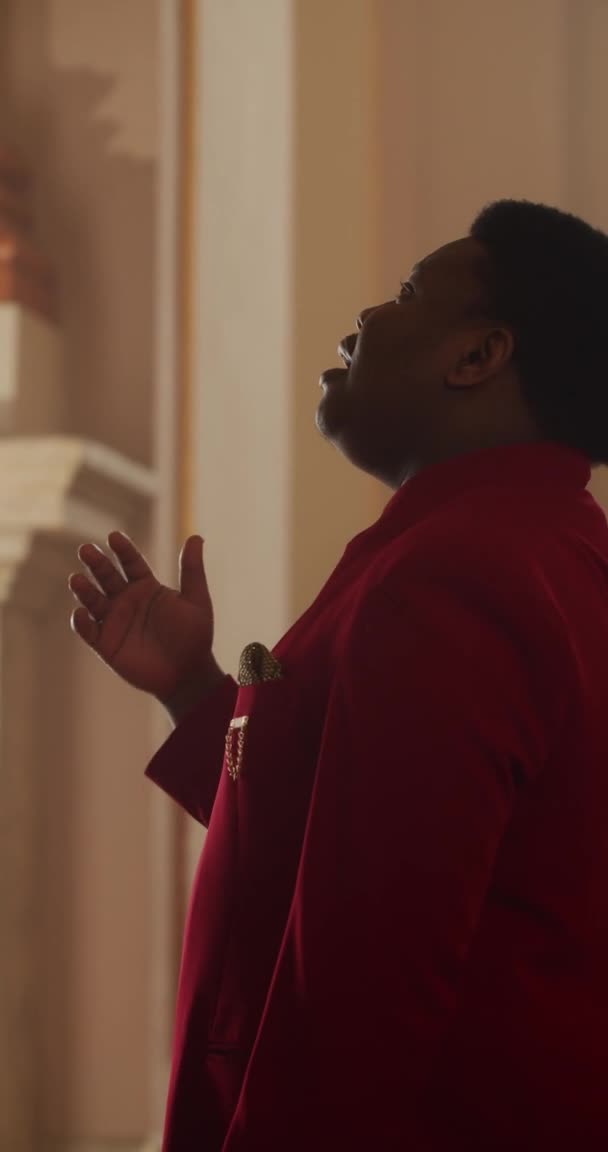Vista lateral do talentoso músico gospel afro-americano em canto de terno vermelho. Jovem realizando emocionalmente música de adoração e corpo em movimento em rima. Vídeo vertical . — Vídeo de Stock