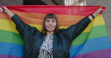 Gökkuşağı bayrağı kaldırıp gülümseyen güzel bir kızın portresi. Bin yıllık güzel bir kadının sokak ortasında durup kameraya bakarken Igbt toplumunu desteklediği ekin manzarası.