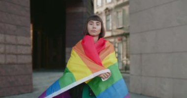 Çekici bir kadının kameraya bakarken kendini gökkuşağı bayraklarıyla kapladığı ekin manzarası. Igbt hareketini destekleyen bin yıllık stil kız portresi.