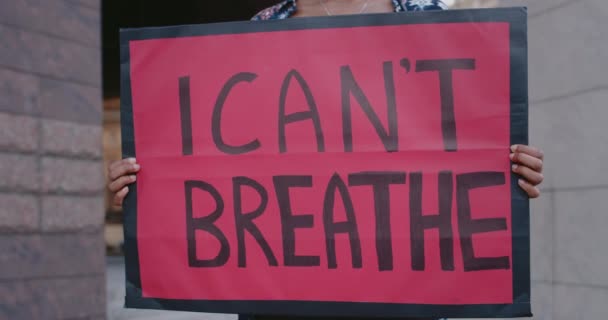 Kvinnliga händer håller banderoll med jag kan inte andas skriva. Närbild av afro amerikan aktivist stödja rörelse mot våld och rasism när de står på gatan. — Stockvideo