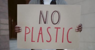 Ekoloji hareketini destekleyen Afro-Amerikan erkek hareketi. Plastik sloganı olmayan ve şehir caddesinde duran karton levhaları tutan ellerinizi yakın tutun. Çevre kirliliği kavramı.