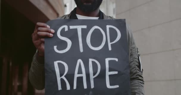 Vista de cerca del activista afroamericano con pancarta con el lema de alto a la violación en la calle de la ciudad. Un tipo barbudo apoyando el movimiento contra el asalto. Concepto de problemas sociales . — Vídeo de stock