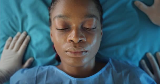 アフリカ系アメリカ人の女の子のトップビュー医療輸送カートに横たわっている。病院に救急車に乗って目を閉じて病気の女性の閉鎖。病気と医療の概念. — ストック動画
