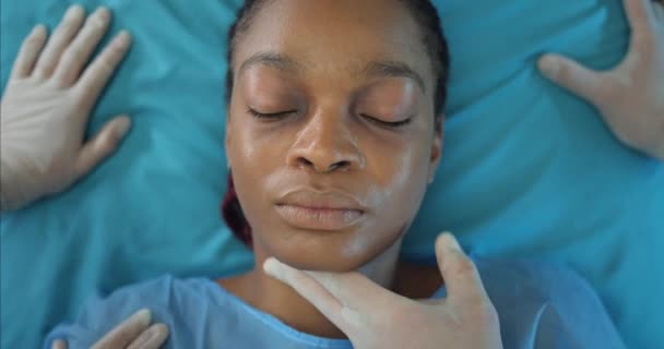 Vue du dessus des médecins mesurant manuellement le pouls d'une jeune femme pendant qu'elle se rend à l'hôpital en ambulance. Gros plan de malade afro inconscient fille américaine couché sur le chariot de transport médical. — Video