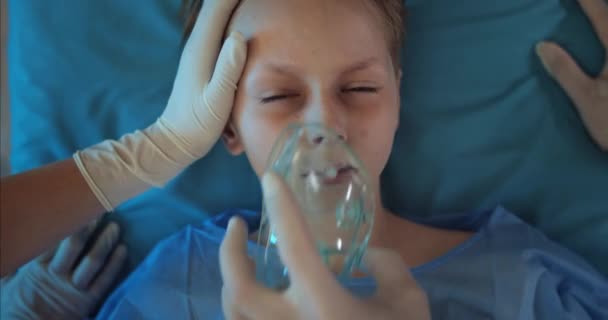 I medici Top View misurano il polso dei bambini mentre vanno in ambulanza in ospedale. Primo piano del bambino malato che guarda alla fotocamera mentre giace sul carrello di trasporto medico. — Video Stock