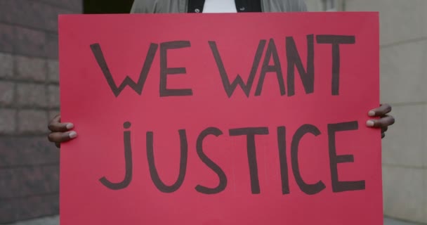 Manliga afrikanska amerikanska händer håller plakat med vi vill ha rättvisa skriva på det. Närbild av kille aktivist stödja rörelse mot brutalitet och rasism när du står på gatan. — Stockvideo