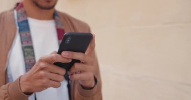 Cep telefonu ekranında daktilo eden erkeklerin yakın görüntüsü. Sokakta yürürken akıllı telefon kullanan bir adamın görüntüsü. İletişim ve teknoloji kavramı.