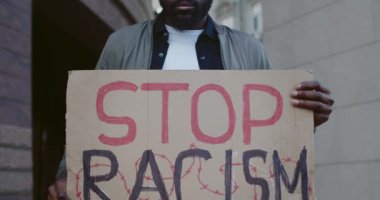 El ele tutuşan adama yaklaş. Irkçılık ifadesini kartondan durdur. Erkek Afro-Amerikan aktivist, şehir sokaklarında ırkçılık karşıtı kampanyayı destekliyor. Eşit insan hakları kavramı.