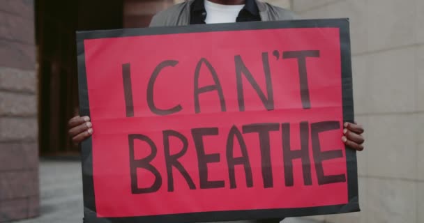 Blisko afrykańskiego mężczyzny trzymającego sztandar z napisem "Nie mogę oddychać". Aktywista wspierający ruch antyrasistowski stojąc na ulicy. Pojęcie praw człowieka. — Wideo stockowe