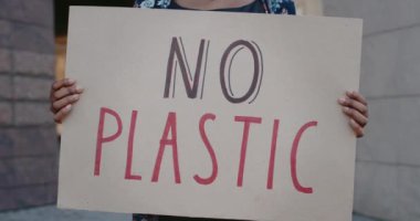Plastik sloganı olmayan ve şehir caddesinde duran karton levhaları tutan ellerinizi yakın tutun. Afro-Amerikan kadın ekoloji hareketini destekliyor. Çevre kirliliği kavramı.