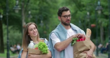 Marketten dönen ve ellerinde yiyecek dolu kağıt torbalarla güzel bir çift. Gözlüklü bir adam güzel karısıyla parkta yürürken nar fırlatıyor..