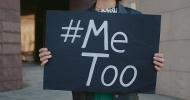 Üzerinde Metoo etiketi olan afişleri tutan ellerin görüntüsü. Kadın eylemci sokakta dururken cinsel saldırıya karşı protestoyu destekliyor. Sosyal sorun kavramı..