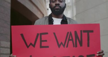 Afro-Amerikan bir adamın pankart tutmasını yakından görmek istiyoruz. Üzerinde adalet yazısı olsun istiyoruz. Sokaklarda dikilen erkek eylemci, şiddete ve ırkçılığa karşı hareketi destekliyor.