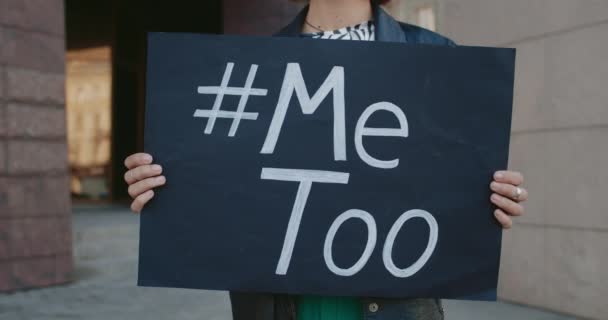 Crop view of hands holding banner with Metoo hashtag on it. Female activist endorsing protest against sexual assault while standing at street .Concept of social problem. — Stock Video
