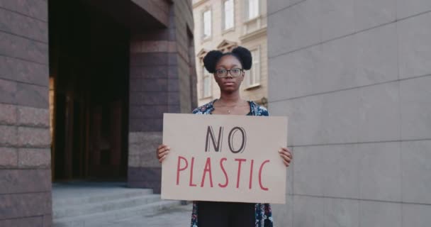 Jovem afro-americana sem cartaz de plástico na rua. Ativista milenar apoiando o movimento de greve ecologia. Conceito de poluição ambiental e salvar a Terra. Ampliar . — Vídeo de Stock