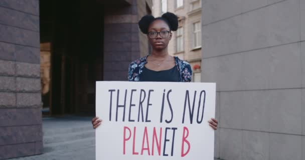 Portré afro-amerikai aktivistáról, akinél ott van a plakát, nincs B bolygó a város utcájában. Fiatal nő, aki támogatja az ökológiát és a tiszta bolygók mozgását. A Föld megmentésének koncepciója. — Stock videók