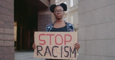 Elinde tutmakta olan Afro-Amerikalı kız portresi ırkçı tabirleri kartondan engelliyor. Şehir caddesinde ırkçılık karşıtı kampanyayı destekleyen kadın eylemci. Eşit insan hakları kavramı.
