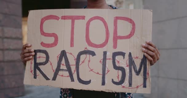 Vista de perto de afro-americanos mãos femininas segurando parar racismo frase papelão na rua da cidade. Feminino activista apoiar campanha anti racismo. Conceito de igualdade de direitos humanos . — Vídeo de Stock